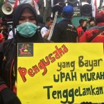 SAMPAIKAN ASPIRASI: Seorang buruh membentangkan kenaikan UMK Jabar saat demonstrasi di Gedung Sate, Kota Bandung beberapa pekan lalu.