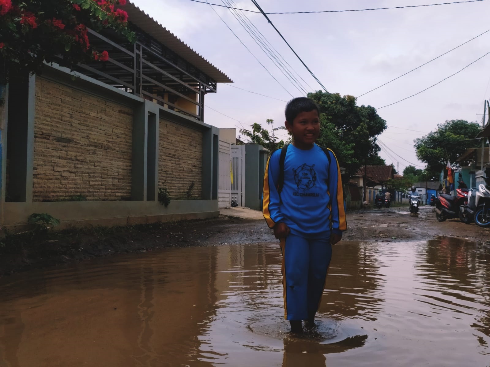 LEWATI KUBANGAN: Seorang anak melintasi jalan berlubang di Desa Mekarmukti Kecamatan Cihampelas, KBB. (Akmal Firamsnyah/Jabar Ekspres)