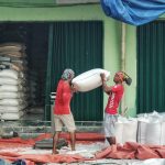 Pekerja di Kios beras Pasar Induk Cipinang tengah melakukan penataan beras