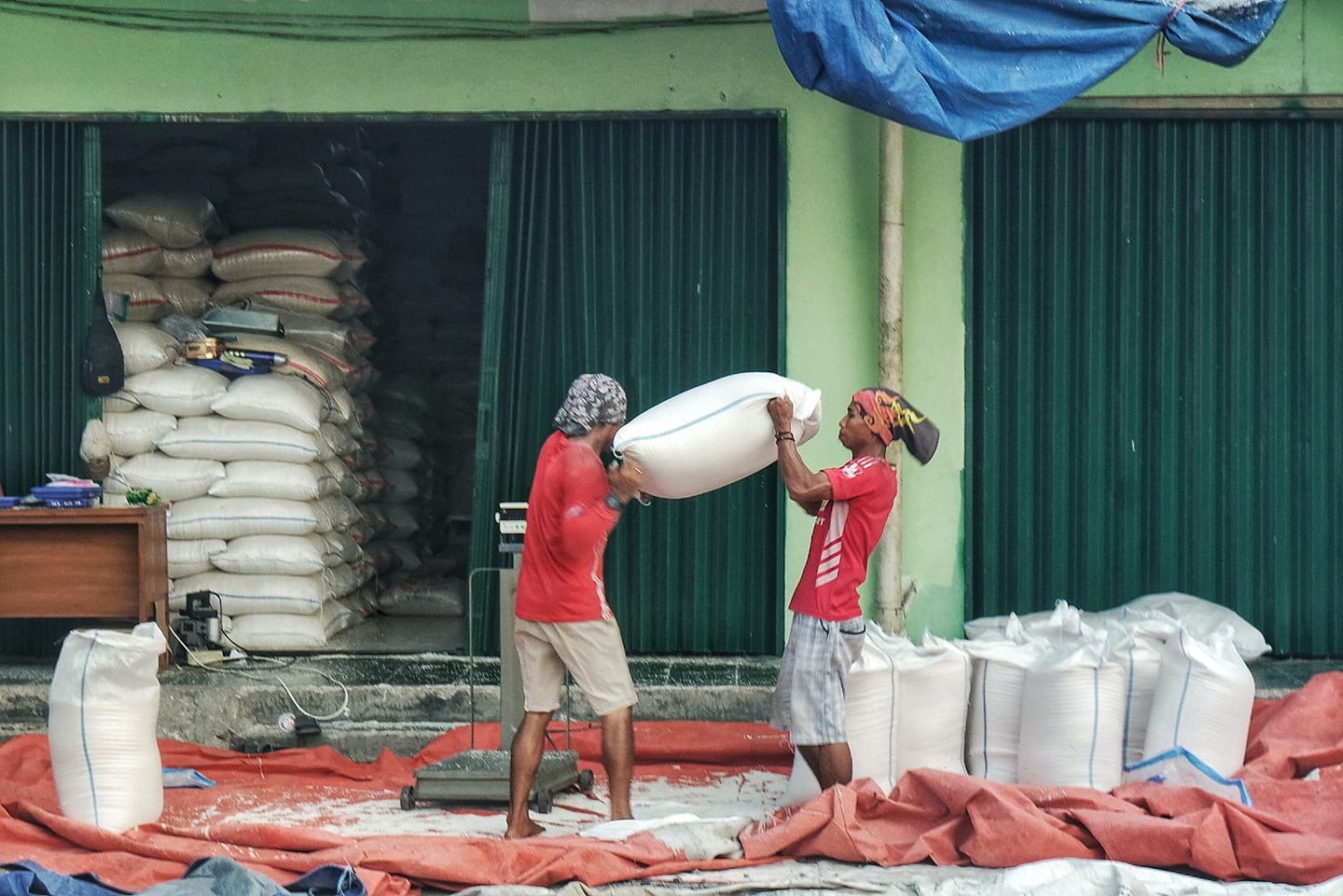 Pekerja di Kios beras Pasar Induk Cipinang tengah melakukan penataan beras