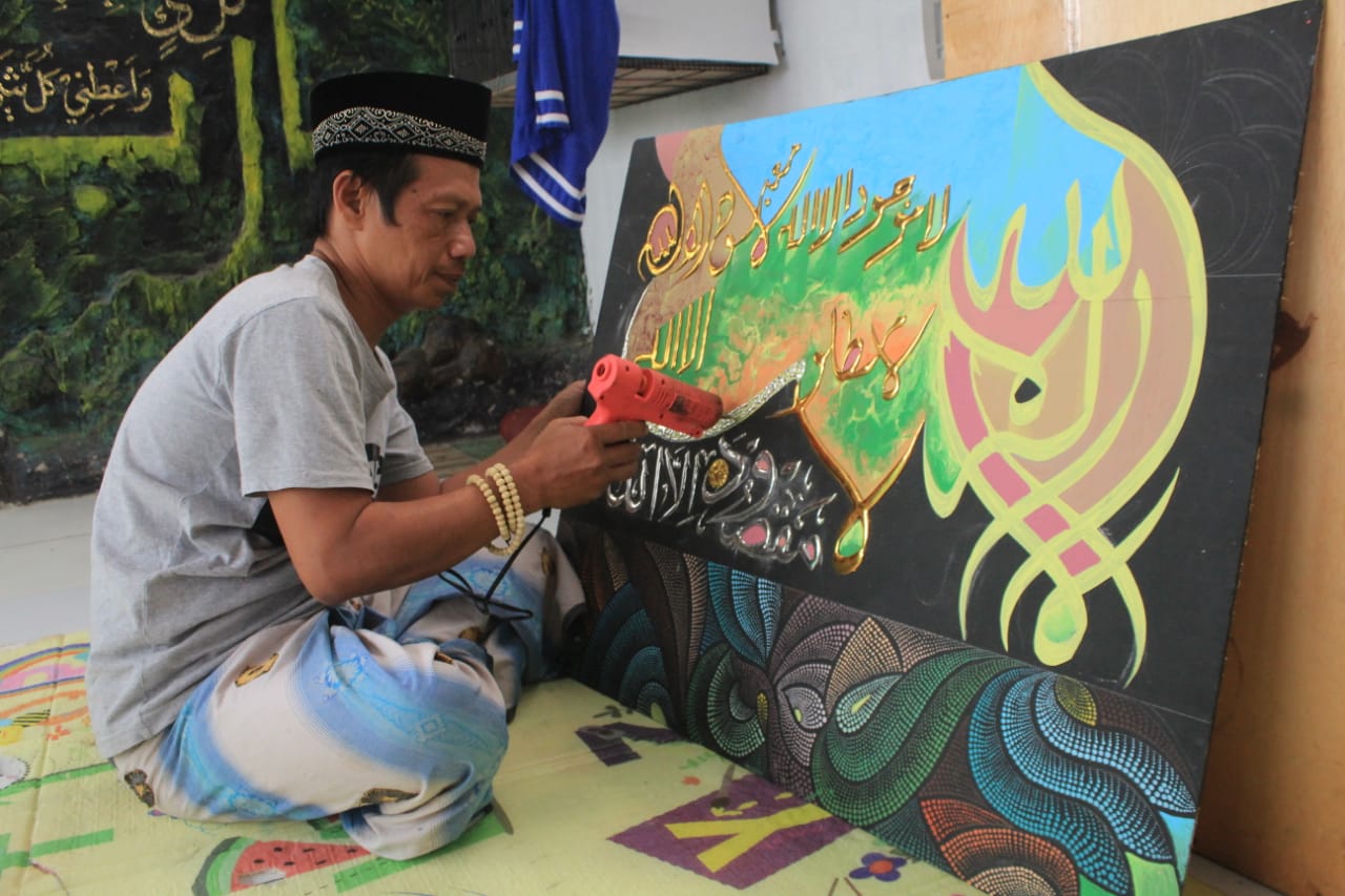Aam Jamaludin saat membuat kaligrafi di rumahnya, Kelurahan Cicaheum, Kiaracondong, Kota Bandung. (HENDRIK MUCHLISON/JABAR EKSPRES)