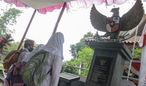 BUKTI SEJARAH: Tiga anak sekolah dasar tengah menghadap Tugu Pancasila yang bergengker di makam Inggit Garnasih di TPU Caringin Porib, Kecamatan Babakan Ciparay, Kota Bandung. (KHOLID/JABAR EKSPRES)