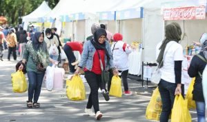 SENANG RIA: Seorang warga sambil membawa barang belanjaan tampak sumringah usai belanja di pasar mudah Bandung.