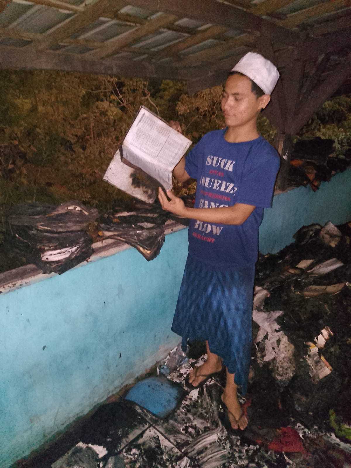 Seorang santri Ponpes Nurul Hidayah saat menunjukkan sejumlah kitab yang ikut terbakar. (istimewa)