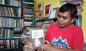 Owner Toko Buku Bandung Deni Rachman menunjukkan salah satu koleksi buku antik yang dimilikinya.