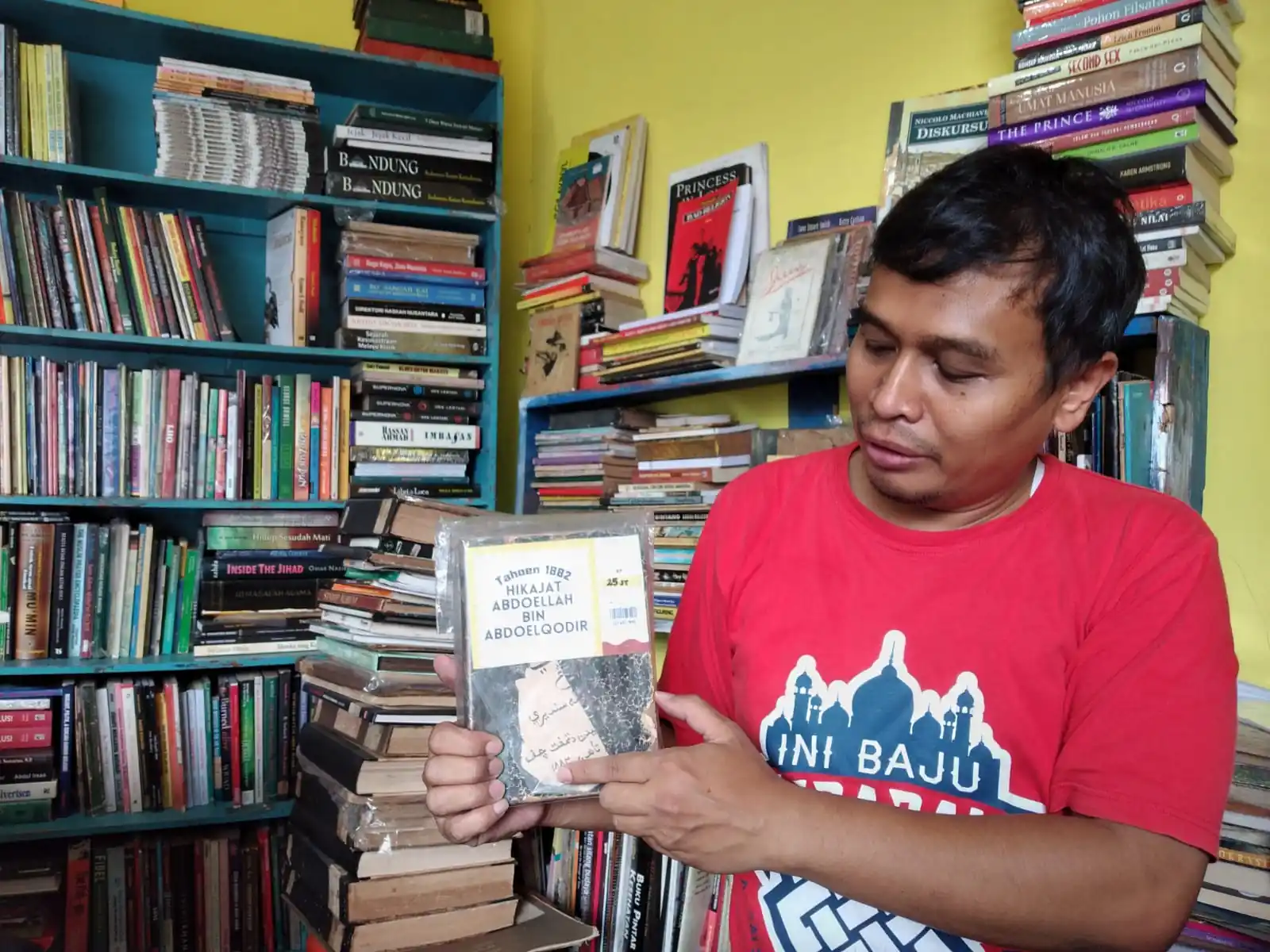 Owner Toko Buku Bandung Deni Rachman menunjukkan salah satu koleksi buku antik yang dimilikinya.