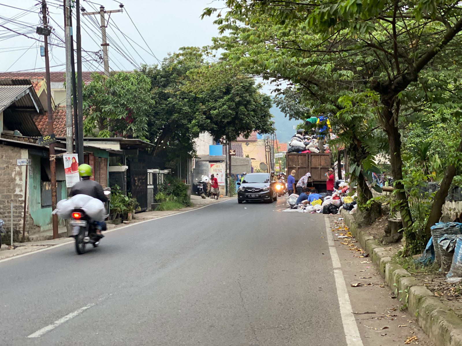 Petugas tengah menangkut sampah yang meluber ke badan jalan di Cimahi Tengah, Kota Cimahi. (Foto Cecep Herdi/Jabar Ekspres)