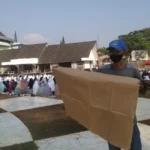 Atang (61) berjualan alas kertas saat pelaksanaan shalat Istisqa di lapang merdeka kota Sukabumi. Foto: Riki/Jabar Ekspres