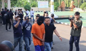 Momen WN (32), pelaku kekerasan terhadap anak kandungnya sendiri, saat digiring oleh pihak Polres Sukabumi.
