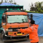 Petugas Dishub Kabupaten Bogor mengatur lalu lintas di Jalan Parung Panjang yang masih dilalui oleh truk diluar jam operasionalnya.