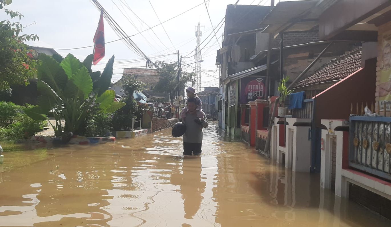 Seorang warga saat melintasi banjir yang mengepung Kampung Bojong Asih, Dayeuhkolot, Kabupaten Bandung, Senin (8/1/2024). Foto Agi Jabar Ekspres