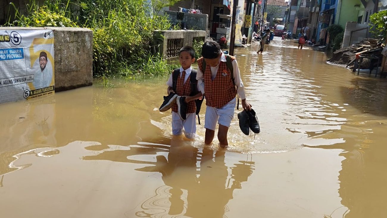 Anak-anak SD saat menerjang banjir yang terjadi di Kampung Bojongasih, Dayeuhkolot, Kabupaten Bandung, Senin (8/1).