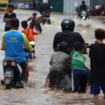 Ilustrasi: Warga Kota Bandung sedang menerjang banjir.