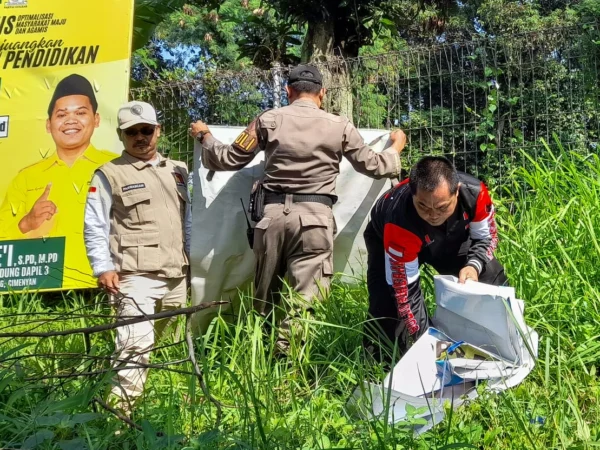 Petugas Bawaslu beserta Satpol PP mencopot APK Parpol yang masih terpasang saat masa tenang Pemilu 2024 di kawasan Jalan Percobaan, Cileunyi, Kabupaten Bandung. (Pandu Muslim/Jabar Ekspres)
