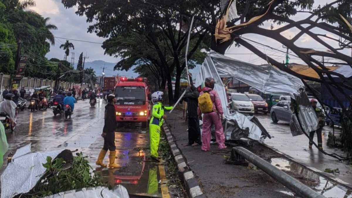 Petugas saat mengevakuasi puing reklamu dan pohon tumbang yang menghalangi jalan Raya Bandung-Garut. Foto Istimewa