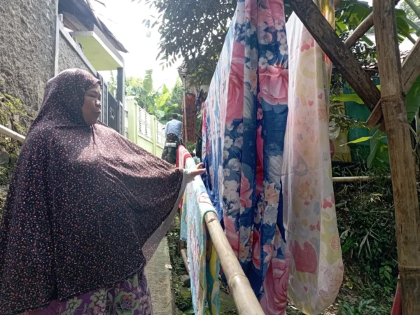 Ibu Kokom saat menjemur pakaian milik warga. Foto : Sandika Fadilah/jabareskpres.com