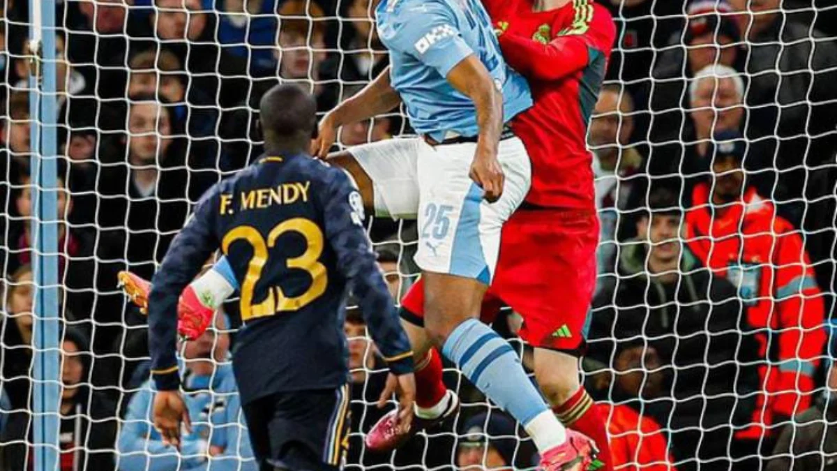 Kiper Real Madrid, Andriy Lunin (merah), saat menghalau bola di udara melawan Manchester City, Kamis (18/4).