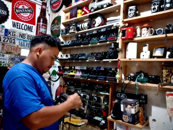 Yosep Tobing sedang membersihkan koleksi kamera jadul miliknya di Pasar Antik Cikapundung.