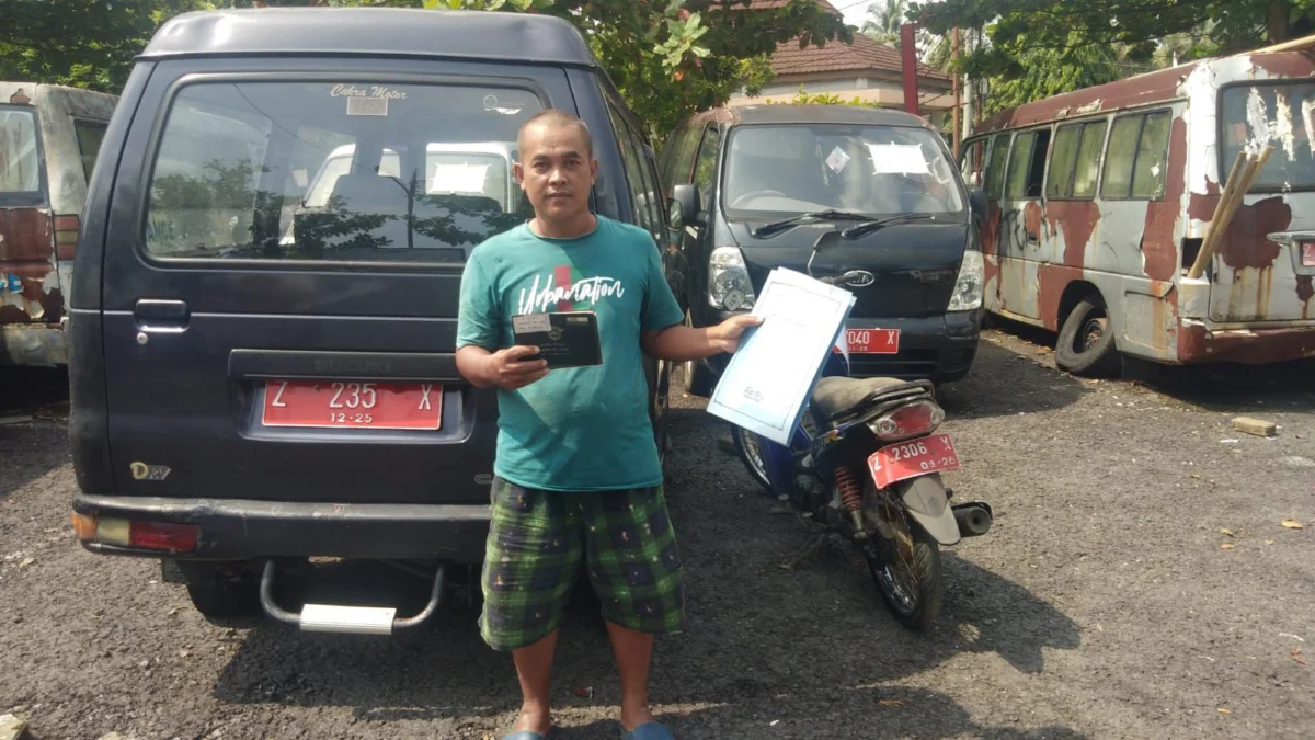 Salah satu pemenang lelang kendaraan Pemkot Banjar menujukkan dokumen kendaraan di area parkiran Perkantoran Purwaharja Kota Banjar baru-baru ini. (Cecep Herdi/Jabar Ekspres)