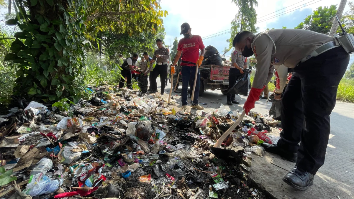 Para petugas kepolisian saat membersihkan tumpukan sampah di jalan Bhayangkara, Soreang, Kabupaten Bandung. Foto Agi