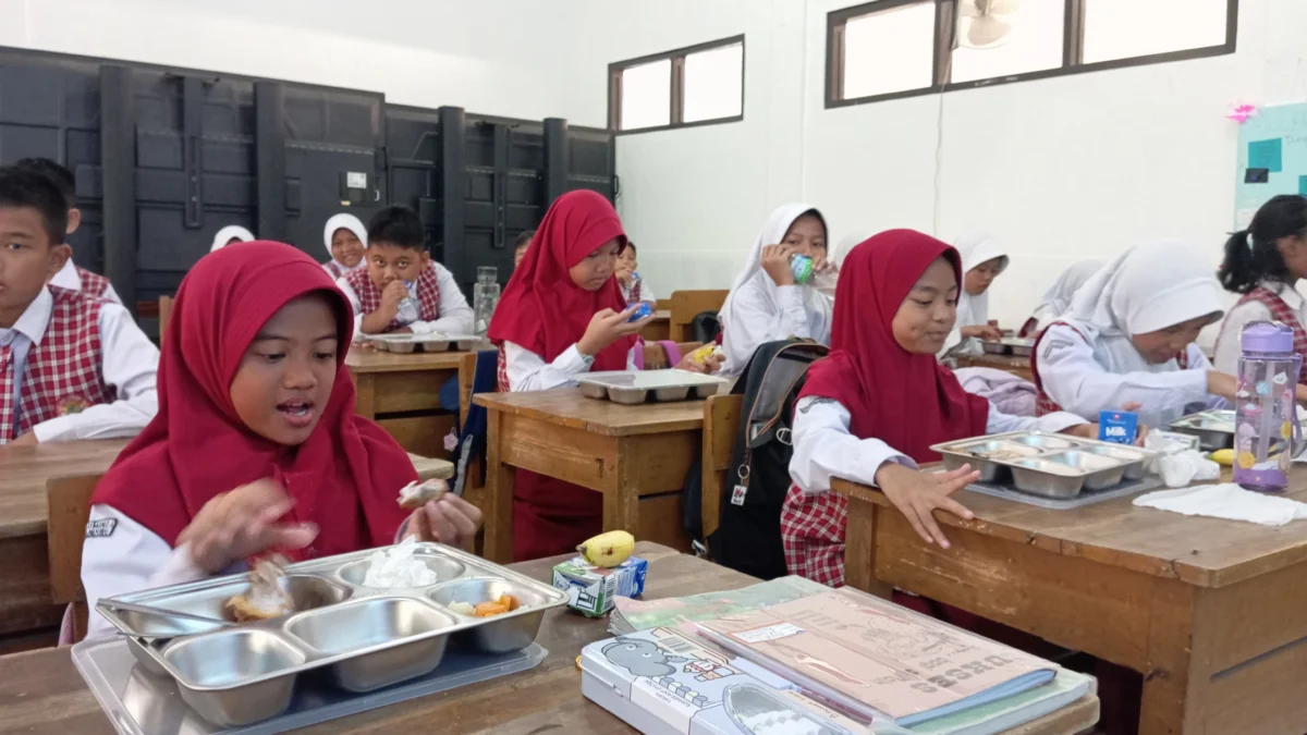 Para murid saat mengambil dan menyantap paket makan siang gratis di SDN 004 Guruminda, Kecamatan Cisaranten Kulon, Selasa (23/7). (Nizar/Jabar Ekspres)