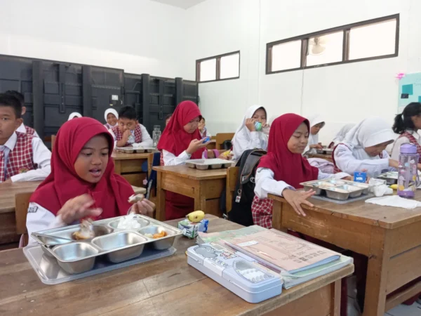 Para murid saat mengambil dan menyantap paket makan siang gratis di SDN 004 Guruminda, Kecamatan Cisaranten Kulon, Selasa (23/7). (Nizar/Jabar Ekspres)