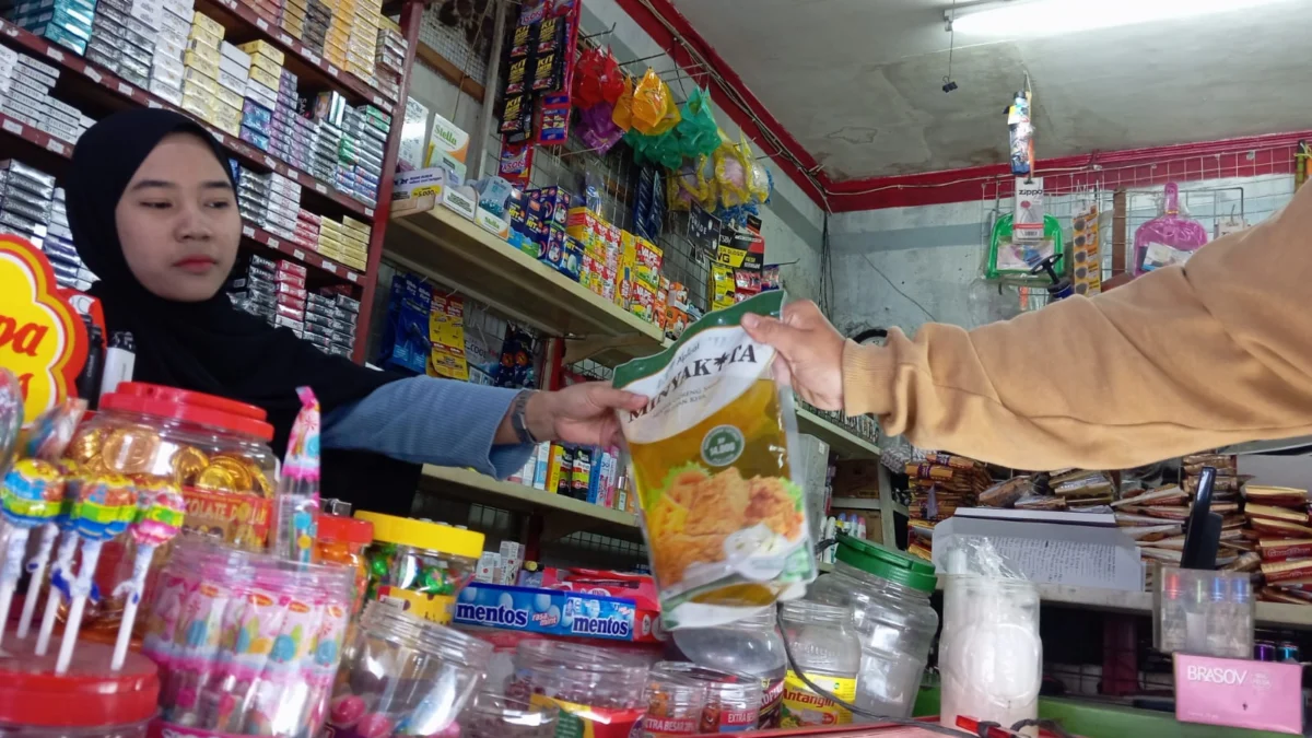 Seorang penjaga toko sedang melayani pembelian minyak goreng bersubsidi Minyak Kita, di Margahayu, Kota Bandung. (Nizar/Jabar Ekspres)