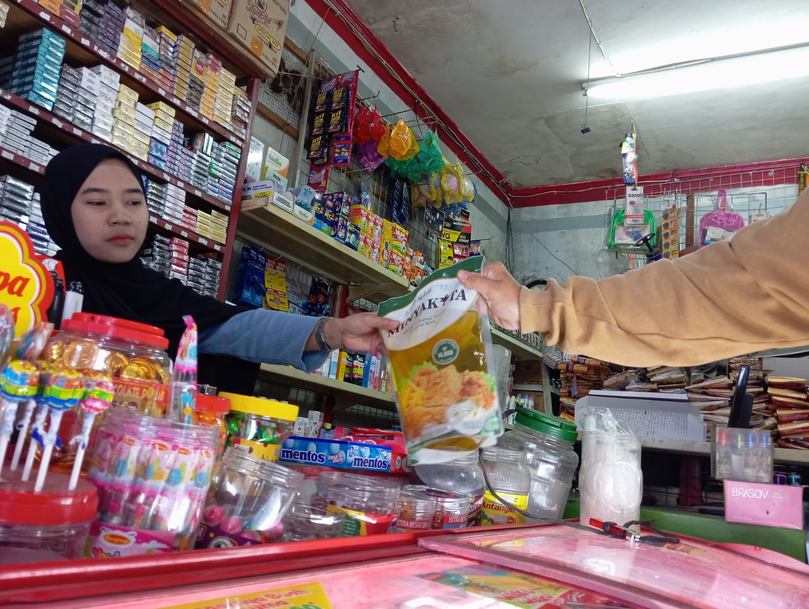 Seorang penjaga toko sedang melayani pembelian minyak goreng bersubsidi Minyak Kita, di Margahayu, Kota Bandung. (Nizar/Jabar Ekspres)