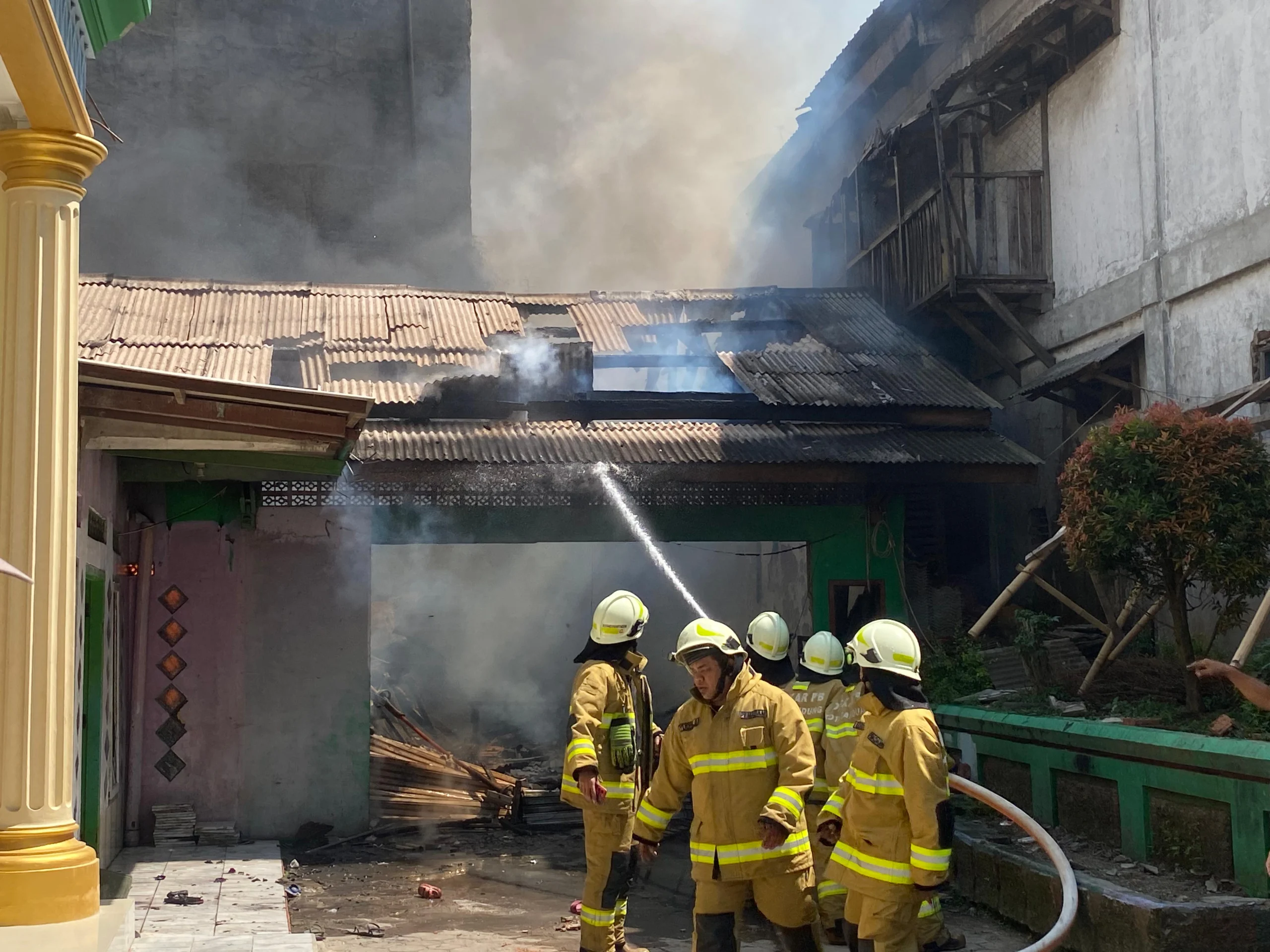 Para petugas pemadam kebakaran tengah memadamkan api yang melahap dua bangunan madrasah, di Babakan Ciparay, Kota Bandung, Minggu (27/7). (Nizar/Jabar Ekspres)