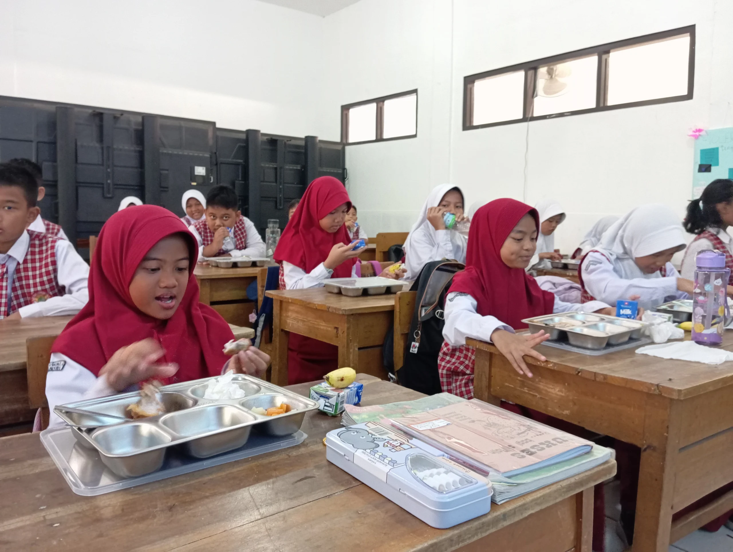 Para murid saat mengambil dan menyantap paket makan siang gratis di SDN 004 Guruminda, Kecamatan Cisaranten Kulon, belum lama ini. (Nizar/Jabar Ekspres)