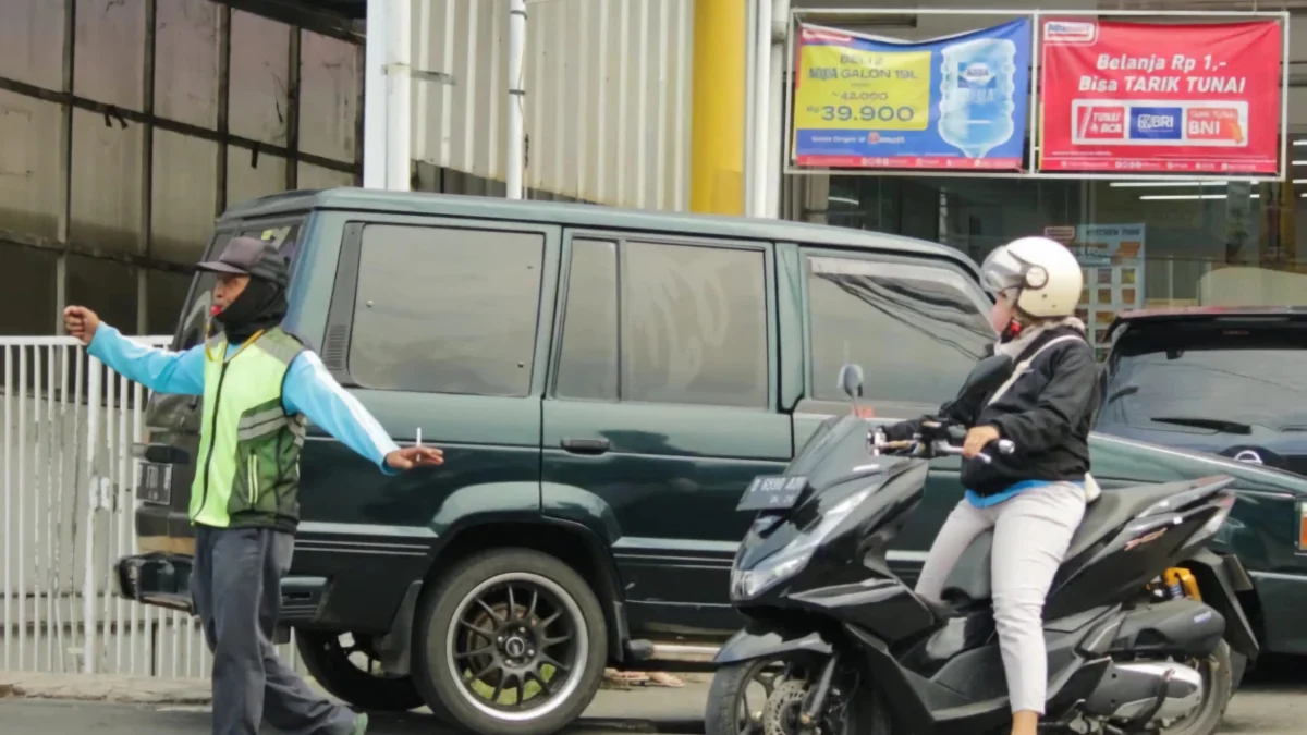 Jukir tengah bertugas di lapak parkiran dan membantu warga mengamankan lajur kendaraan di kawasan Bandung Timur. (Jabar Ekspres)