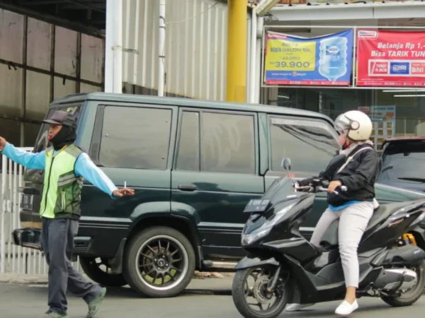 Jukir tengah bertugas di lapak parkiran dan membantu warga mengamankan lajur kendaraan di kawasan Bandung Timur. (Jabar Ekspres)