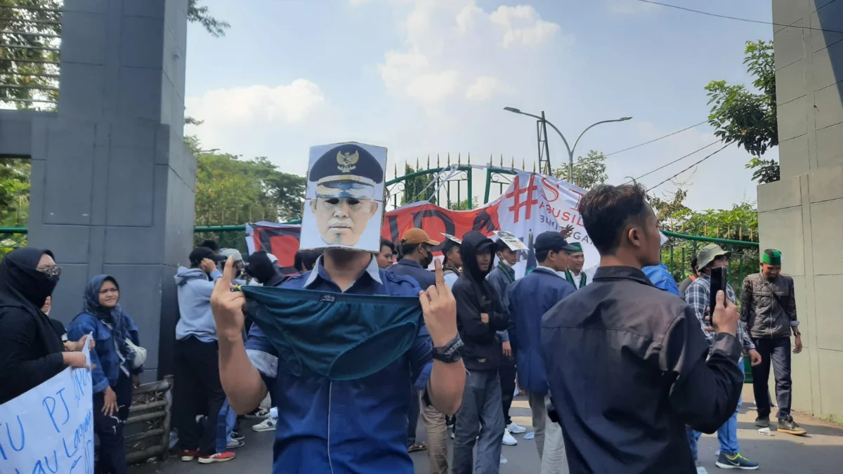 Seorang massa aksi membawa celana dalam dengan menggunakan topeng wajah Pj Bupati Bogor, sebagai bentuk protes dalam aksi di Bogor, Jumat (6/9). (Sandika FadilahJabar Ekspres)