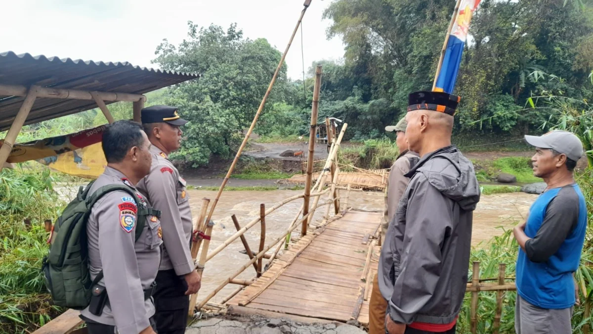 PIhak kepolisian saat mengecek kondisi jembatan yang menghubungkan dua desa Pacet dan Majalaya terputus akibat derasnya debit air anak sungai citarum. Foto Istimewa