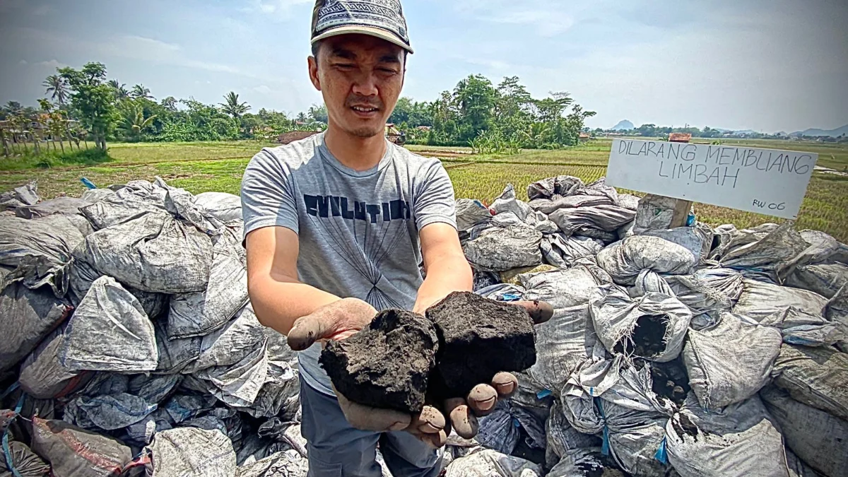 Salah seorang warga Kampung Rongga, Desa/Kecamatan Cihampelas, Bandung Barat saat memperlihatkan limbah batu bara yang dibuang sembarangan. Kamis (17/10). Dok Jabar Ekspres