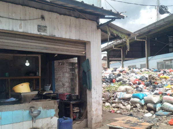 Pedagang kelapa, Dani Ramdani (30) tengah mencuci tangan usai membersihkan kiosnya yang bersebelahan dengan gunungan sampah di Pasar Sehat Cileunyi, Kabupaten Bandung. (Yanuar/Jabar Ekspres)