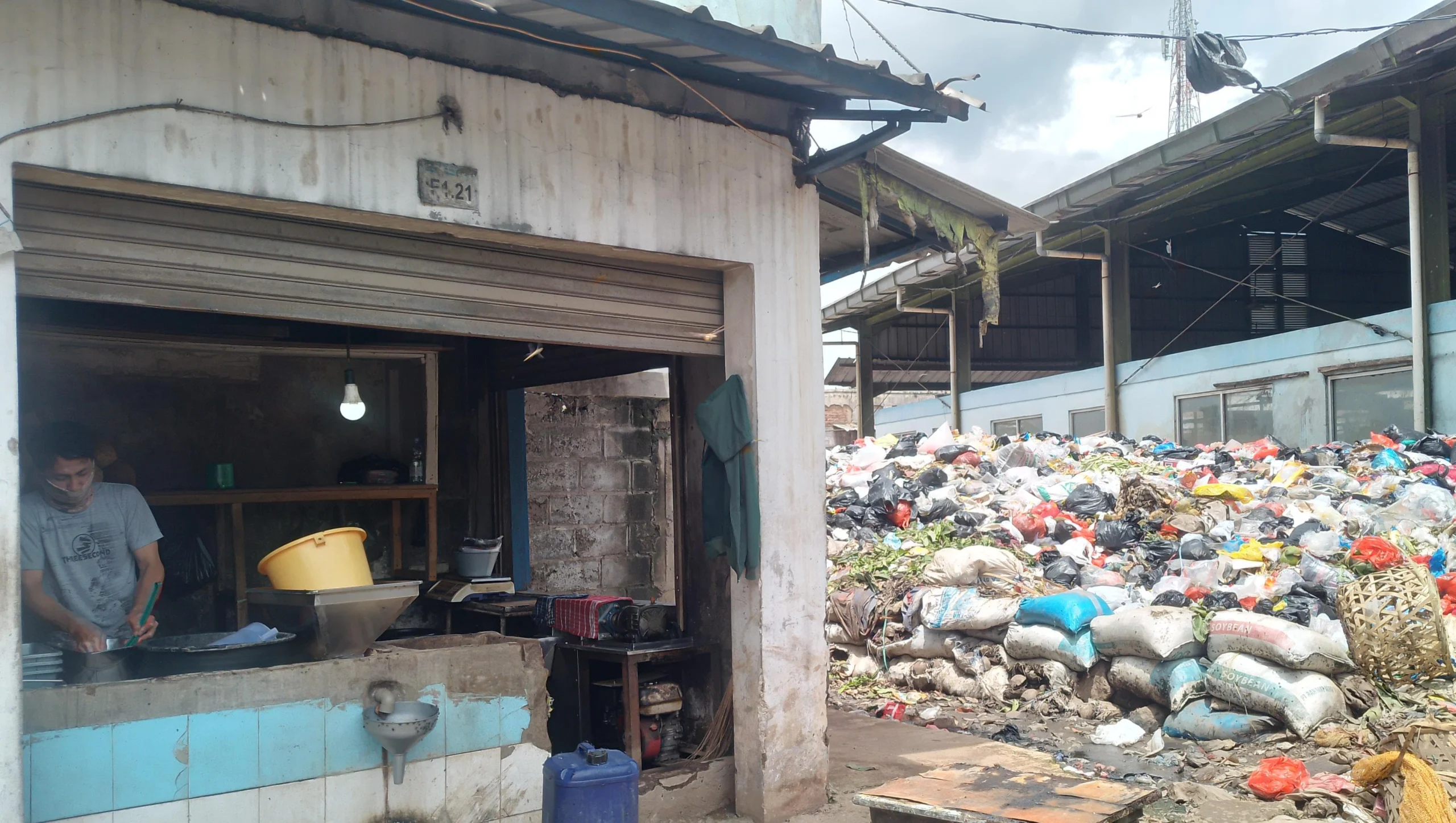 Pedagang kelapa, Dani Ramdani (30) tengah mencuci tangan usai membersihkan kiosnya yang bersebelahan dengan gunungan sampah di Pasar Sehat Cileunyi, Kabupaten Bandung. (Yanuar/Jabar Ekspres)