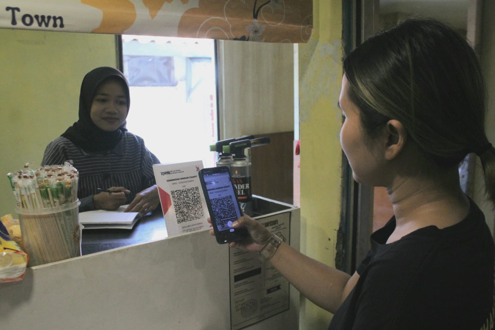 Salah satu pembeli saat membayar memanfaatkan QRIS di Pasar Cihapit Kota Bandung, Jumat (11/10).