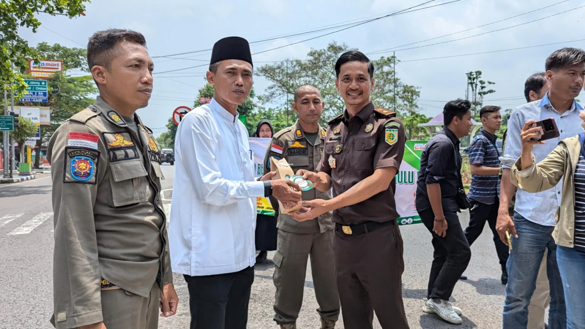 Kasi Intel Kejaksaan Negeri Ciamis Arief Gunadi memberikan bingkisan dan atiker anti korupsi kepada salah satu warga Ciamis, di sekitar Alun Alum Ciamis, Jawa Barat, Selasa 22 Oktober 2024. (Cecep Herdi/Jabar Ekspres)