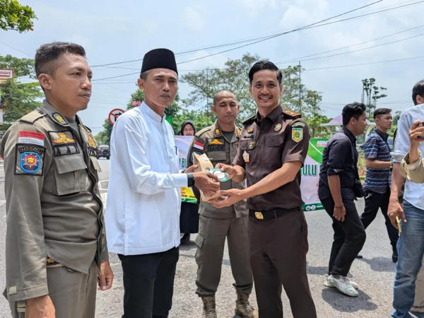 Kasi Intel Kejaksaan Negeri Ciamis Arief Gunadi memberikan bingkisan dan atiker anti korupsi kepada salah satu warga Ciamis, di sekitar Alun Alum Ciamis, Jawa Barat, Selasa 22 Oktober 2024. (Cecep Herdi/Jabar Ekspres)