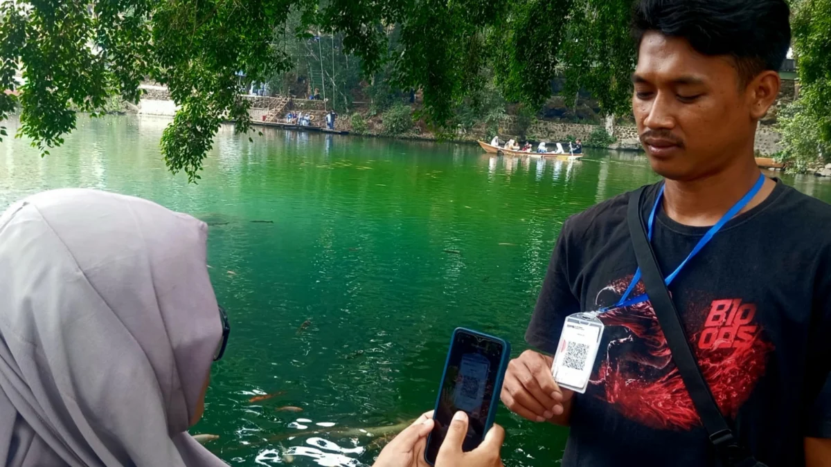 DIGITAL : Salah satu wisatawan saat membayar wahana perahu memanfaatkan QRIS di Telaga Biru Cicerem, Minggu (20/10). (Hendrik Muchlison)