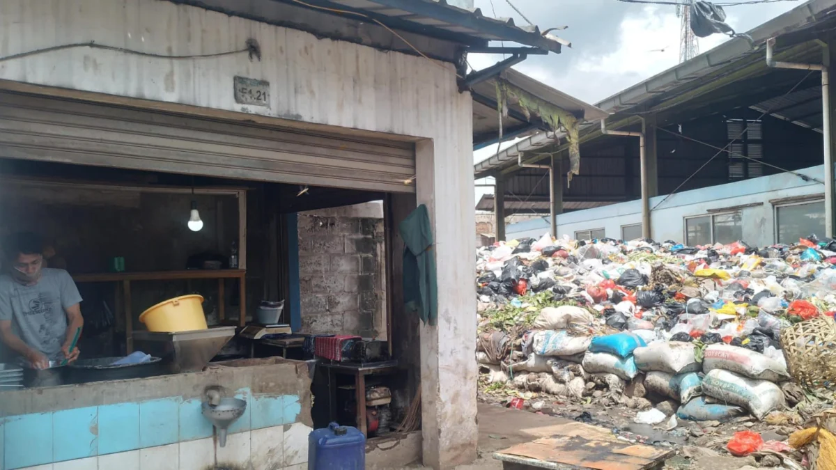 Pedagang kelapa, Ramdani (30) tengah mencuci tangan usai membersihkan kiosnya yang bersebelahan dengan gunungan sampah di Pasar Sehat Cileunyi, Kabupaten Bandung. (Yanuar/Jabar Ekspres)