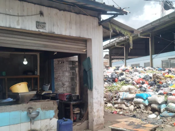 Pedagang kelapa, Ramdani (30) tengah mencuci tangan usai membersihkan kiosnya yang bersebelahan dengan gunungan sampah di Pasar Sehat Cileunyi, Kabupaten Bandung. (Yanuar/Jabar Ekspres)