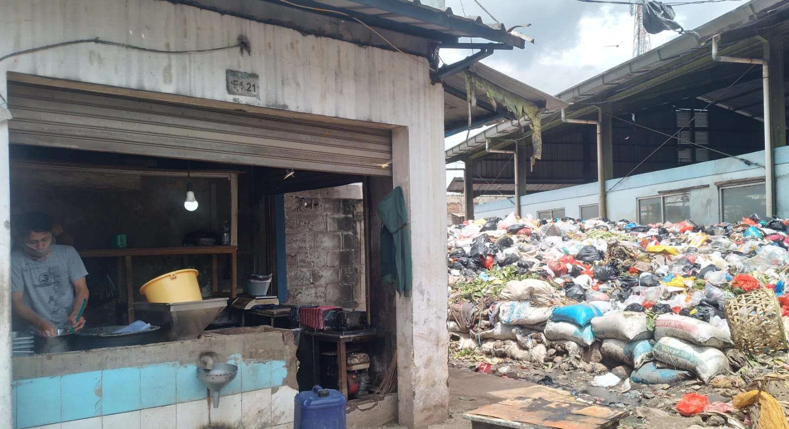 Pedagang kelapa, Ramdani (30) tengah mencuci tangan usai membersihkan kiosnya yang bersebelahan dengan gunungan sampah di Pasar Sehat Cileunyi, Kabupaten Bandung. (Yanuar/Jabar Ekspres)