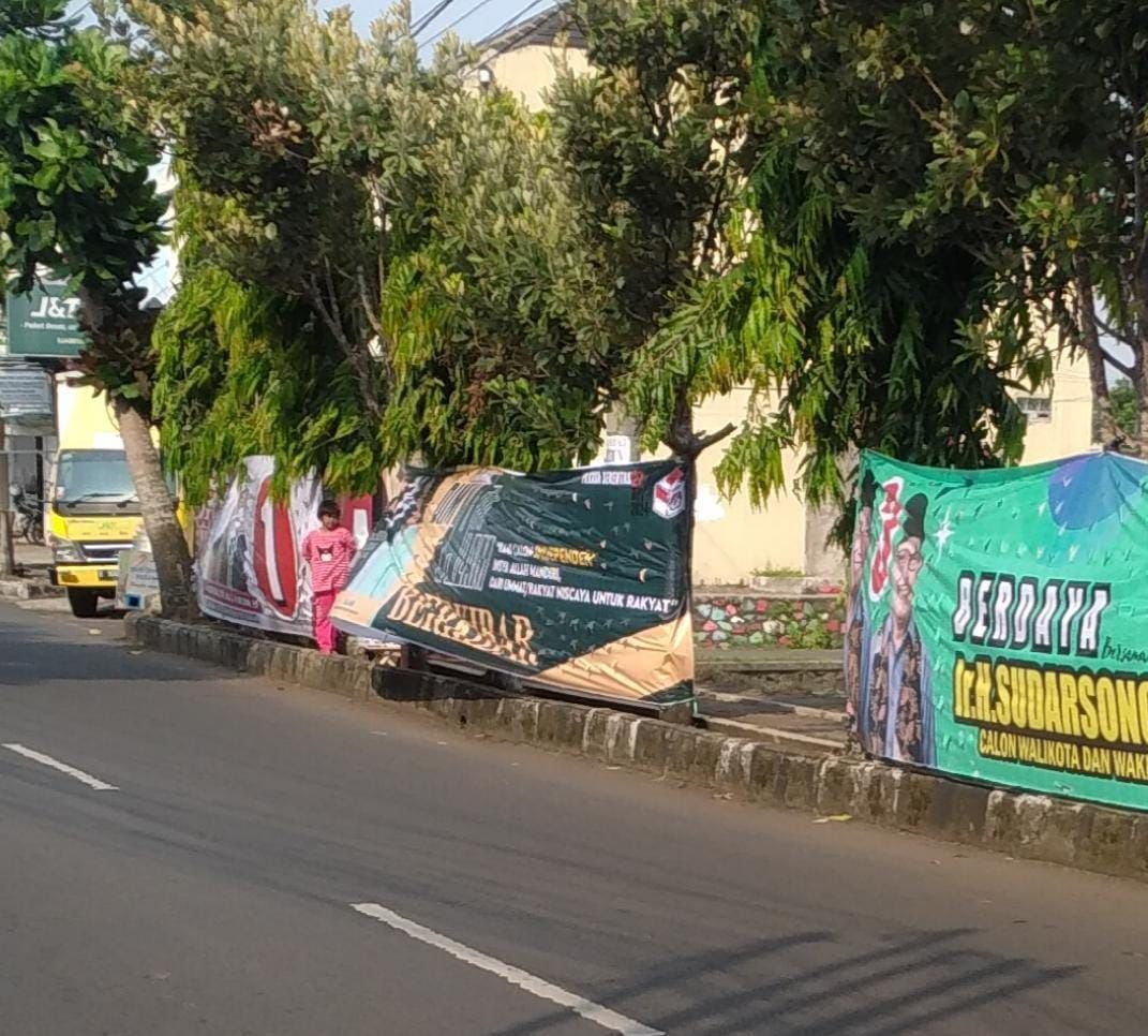 Beberapa Alat Peraga Kampanye (APK) yang diduga difasilitasi oleh KPU Banjar pernah dipasang di tempat yang dilarang, yakni di pohon samping jalan raya. (Cecep Herdi/Jabar Ekspres)