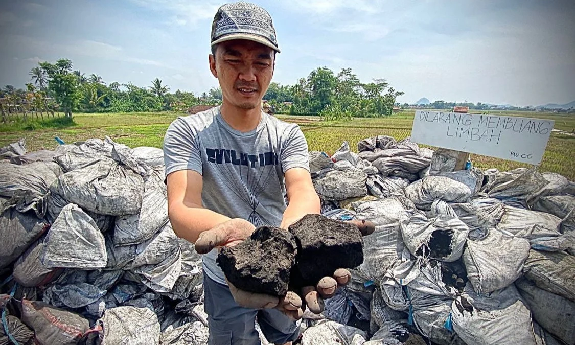 Salah satu warga saat memperlihatkan limbah hasil pembakaran batu bara di Jalan Irigasi, Kampung Rongga, Desa/Kecamatan Cihampelas. Dok Jabar Ekspres