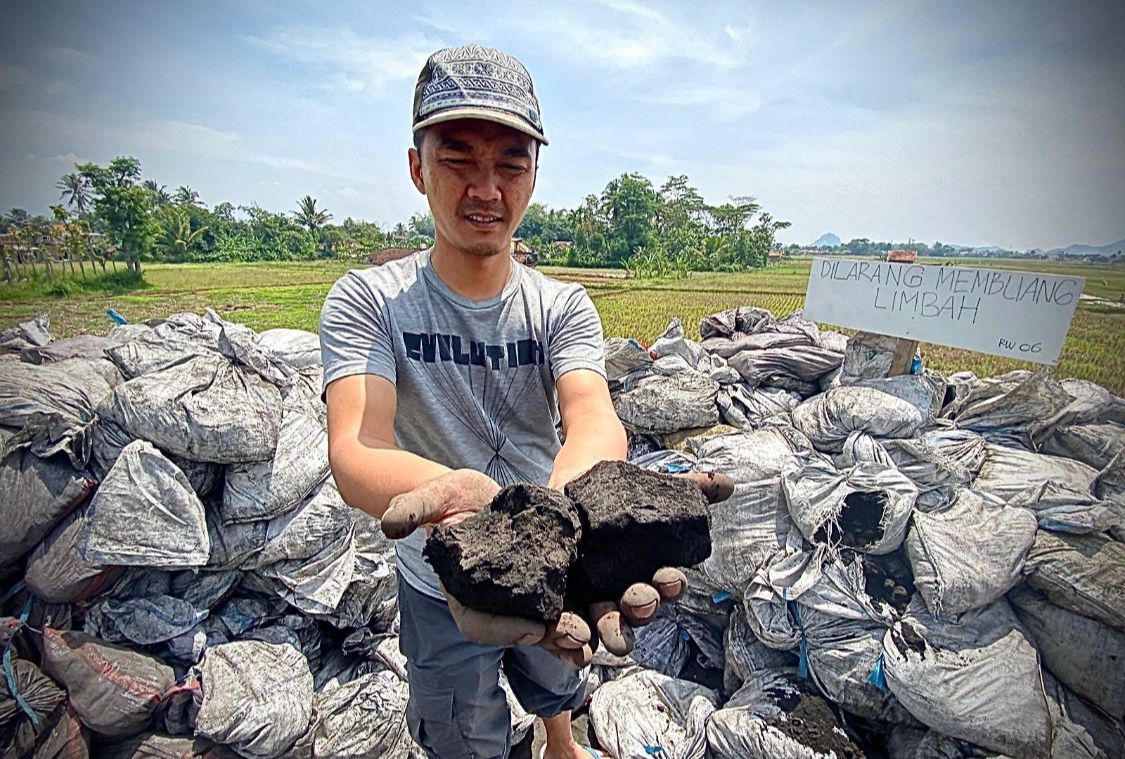 Salah satu warga saat memperlihatkan limbah hasil pembakaran batu bara di Jalan Irigasi, Kampung Rongga, Desa/Kecamatan Cihampelas. Dok Jabar Ekspres