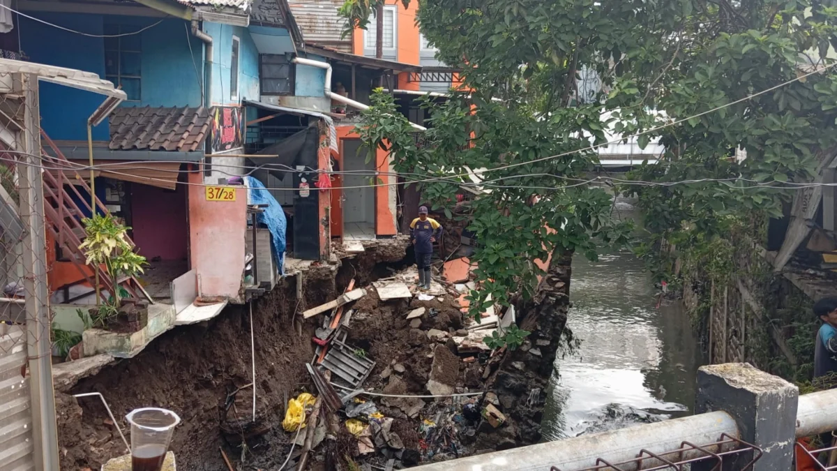 Seorang petugas tengah mengevakuasi sejumlah material bangunan di sekitar rumah terdampak saluran kirmir jebol, Kelurahan Arjuna, Kecamatan Cicendo, Kota Bandung, pada Senin (18/11). (NIZAR/JABAR EKSPRES)