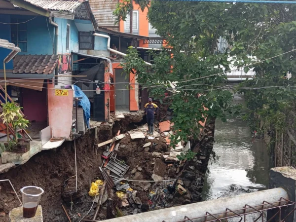 Seorang petugas tengah mengevakuasi sejumlah material bangunan di sekitar rumah terdampak saluran kirmir jebol, Kelurahan Arjuna, Kecamatan Cicendo, Kota Bandung, pada Senin (18/11). (NIZAR/JABAR EKSPRES)