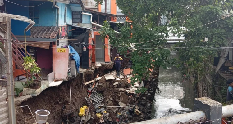 Seorang petugas tengah mengevakuasi sejumlah material bangunan di sekitar rumah terdampak saluran kirmir jebol, Kelurahan Arjuna, Kecamatan Cicendo, Kota Bandung, pada Senin (18/11). (NIZAR/JABAR EKSPRES)